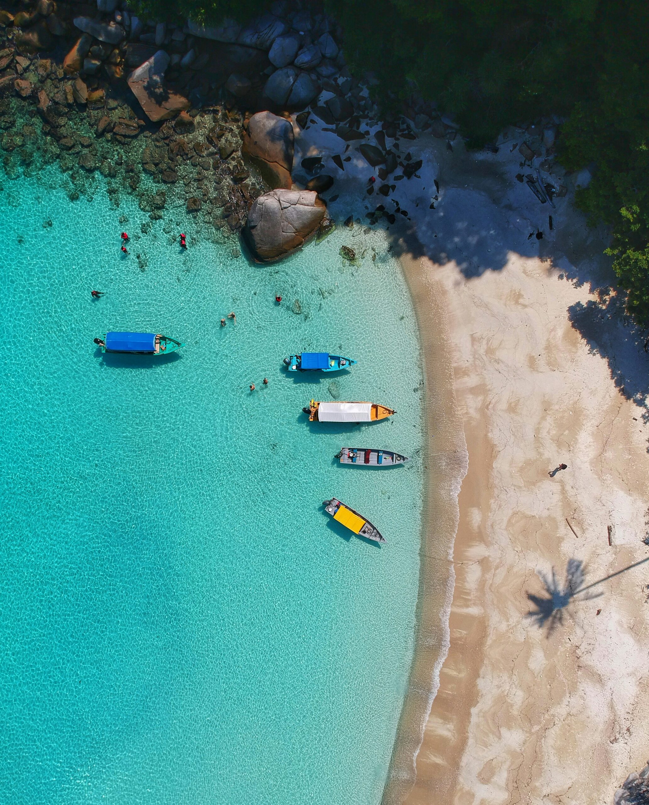 Nos packs de voyage sur mesure. Vue aérienne d'une plage paradisiaque avec des petits bateaux, offrant un cadre idyllique pour des vacances de rêve.