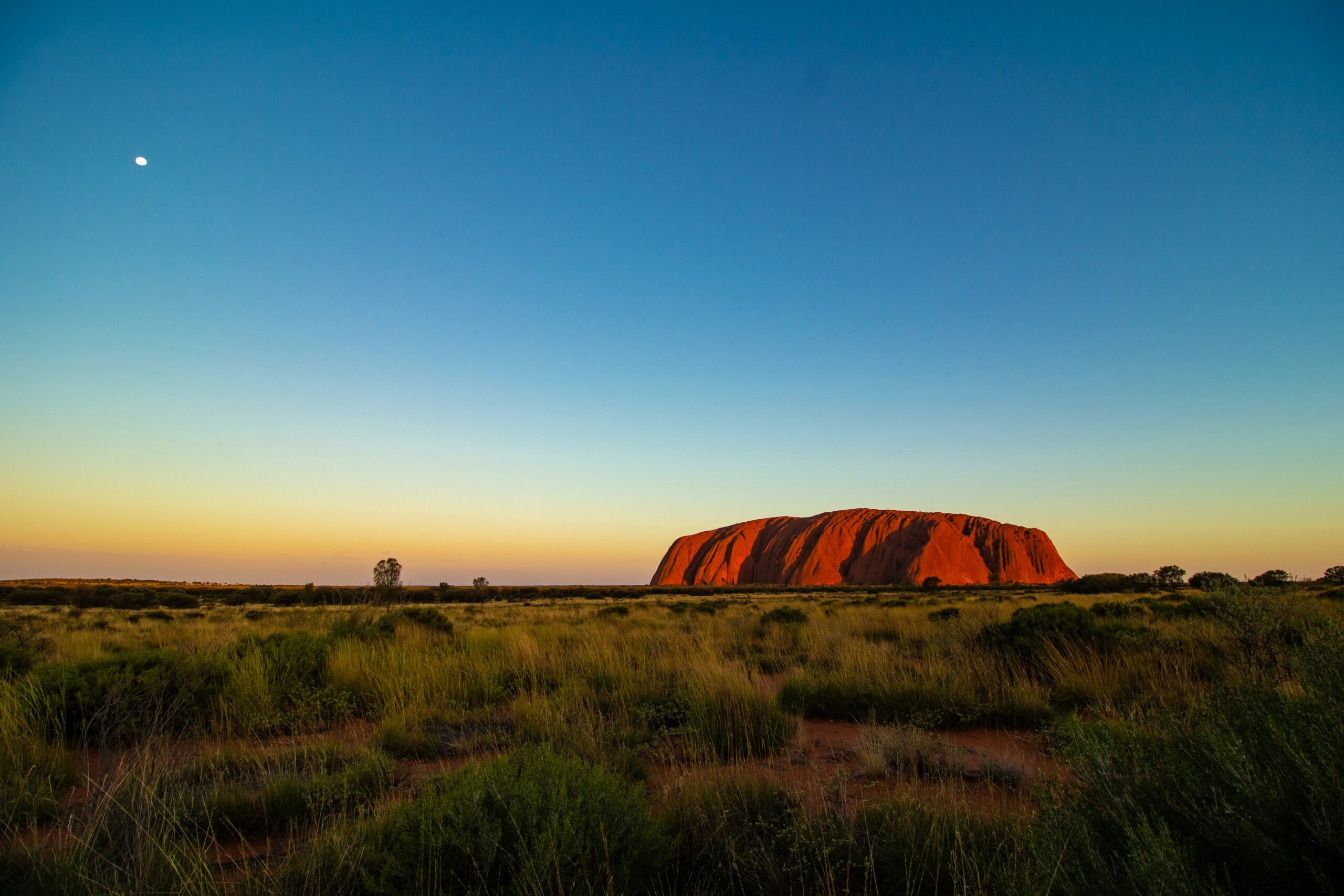 Kavanaia Monolithe d'Uluru au coucher du soleil en Australie avec ciel orangé et paysage désertique